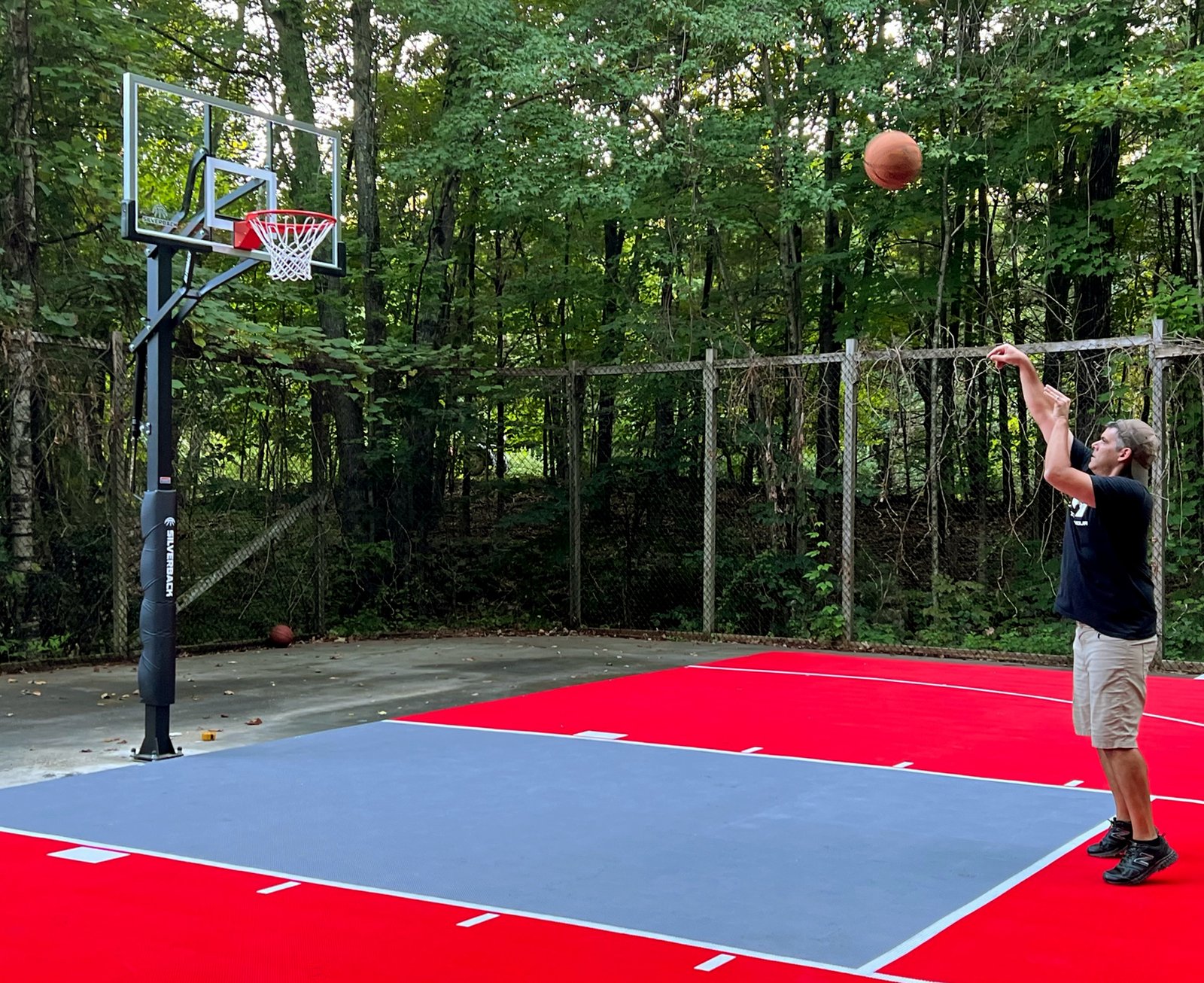 A player shooting a basketball on a custom backyard court built with Outdoor Sport Courts interlocking tiles