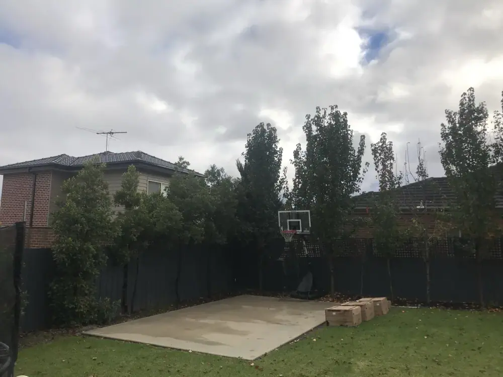 A prepared concrete slab in a Dural, NSW backyard with the court tiles stacked ready to lay